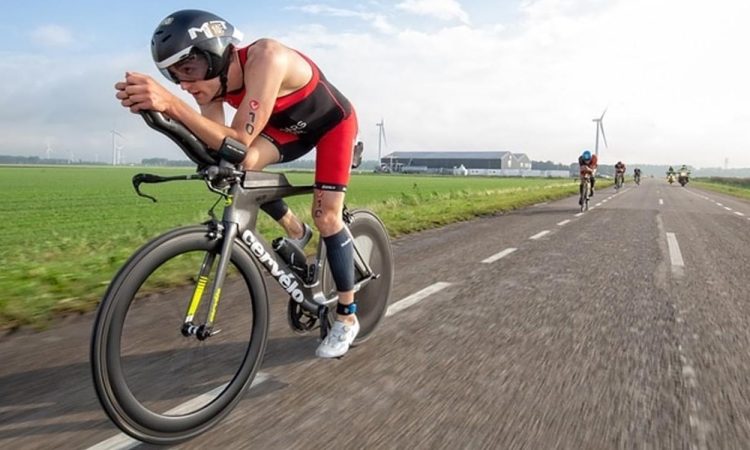 Image of three triathlon cyclists riding on a winding road through a mountainous landscape under a cloudy sky. This demonstrated the benefits of zone 2 training