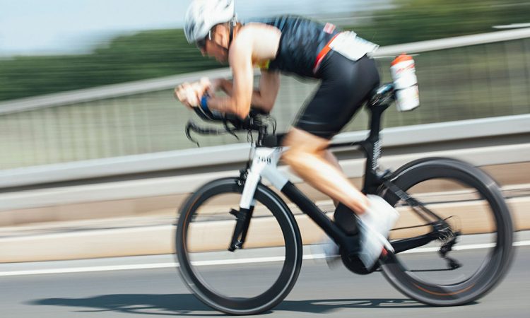 Image of cyclist in helmets riding on a road during a triathlon cycling stage.
