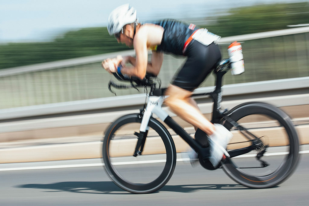 Image of cyclist in helmets riding on a road during a triathlon cycling stage.