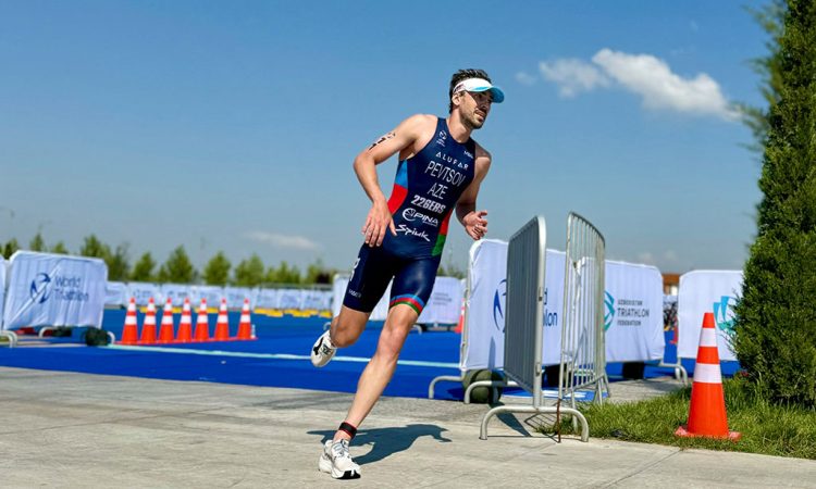 Image of triathletes running on a paved course with race numbers, focused expressions, and spectators visible along the route.